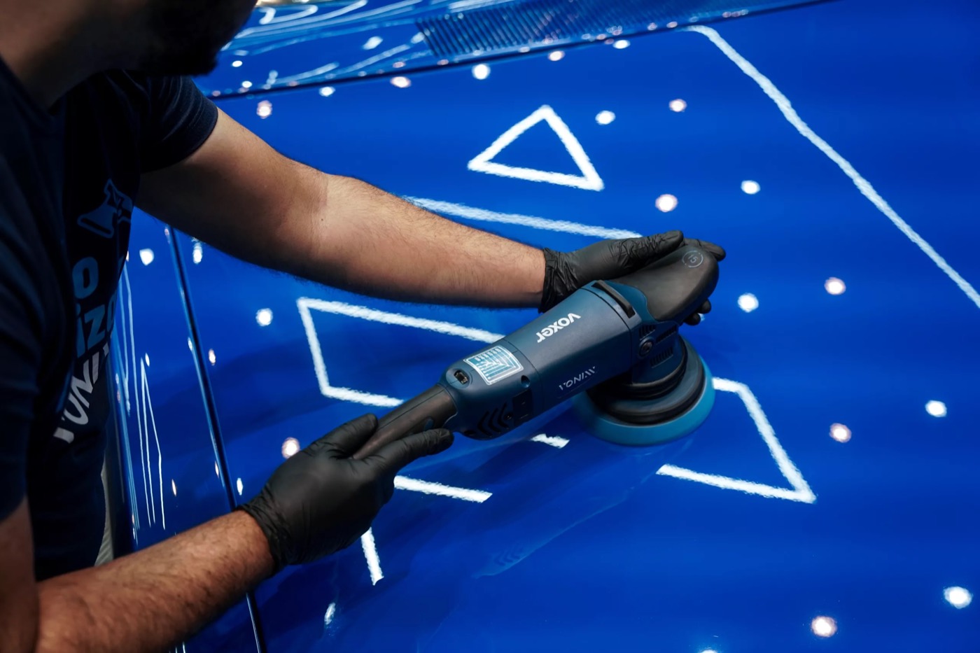 Pulido de la pintura azul de un auto con pulidora de doble acción