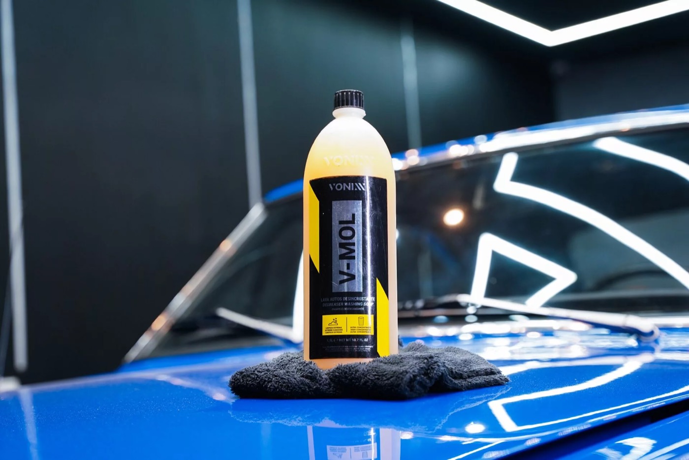 Botella de shampoo V-Mol sobre el cofre azul de un auto